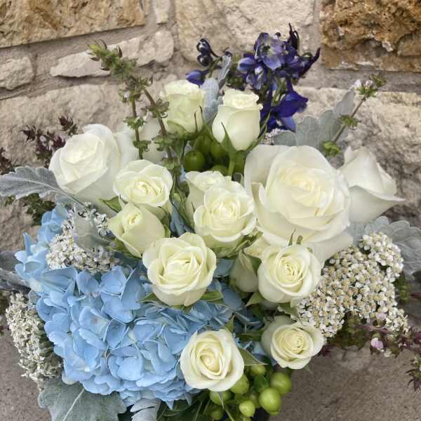 White roses with blue hydrangea and purple flowers in a compact bouquet