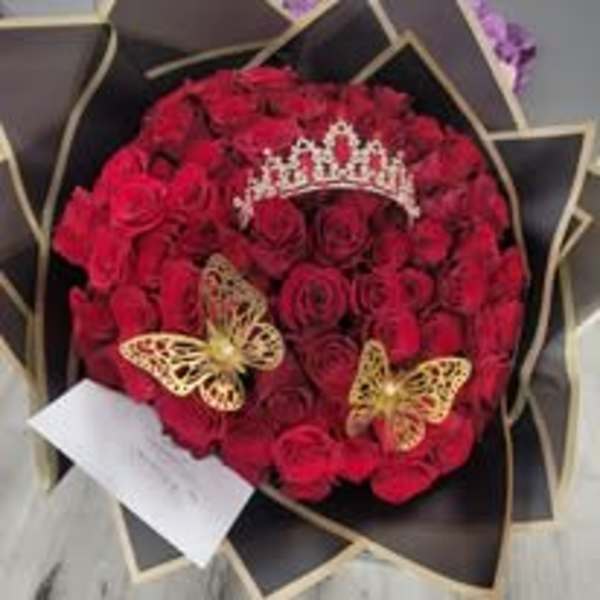 Round bouquet of red roses with a tiara and butterfly decorations