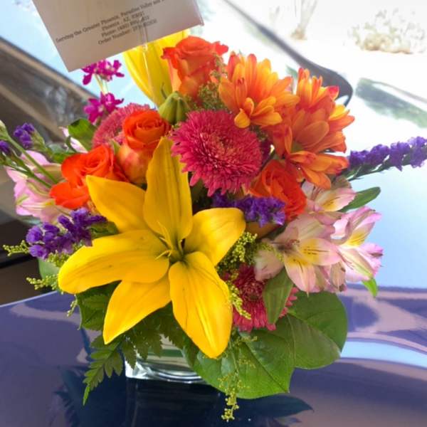 Bright mixed bouquet in a glass vase with yellow lilies and orange flowers