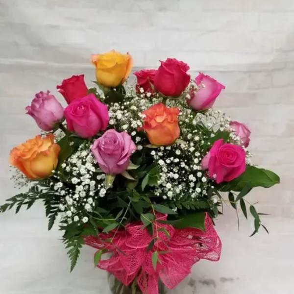 Bouquet of multicolored roses in a glass vase with pink ribbon