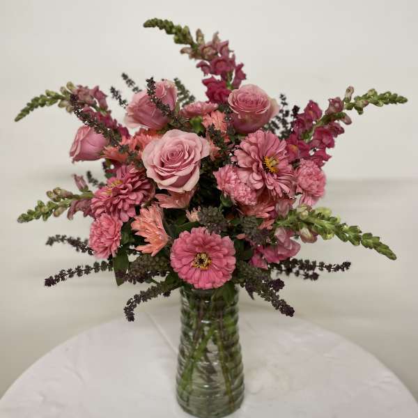 Pink roses and mixed pink flowers in a clear glass vase