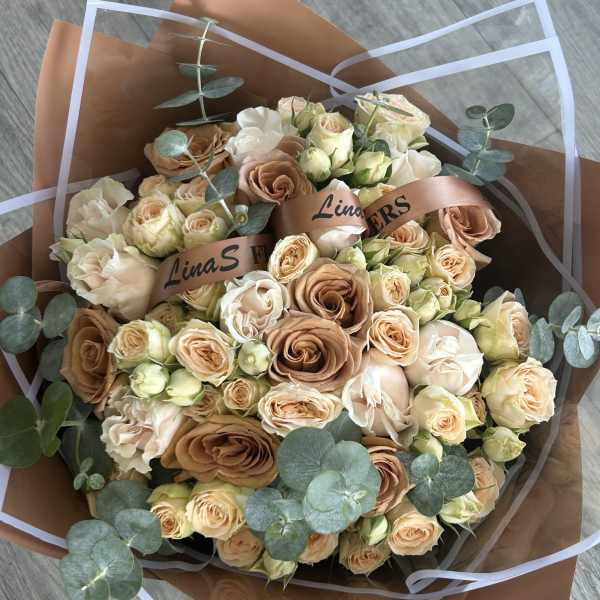 Bouquet of peach and cream roses with eucalyptus in brown wrap