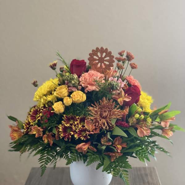 Mixed bouquet in a white vase with yellow, pink, and burgundy flowers