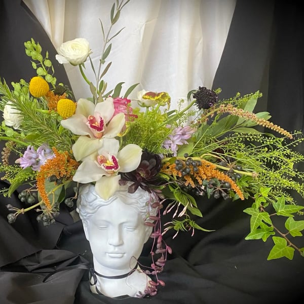 Floral arrangement on a white bust with white orchids and mixed blooms