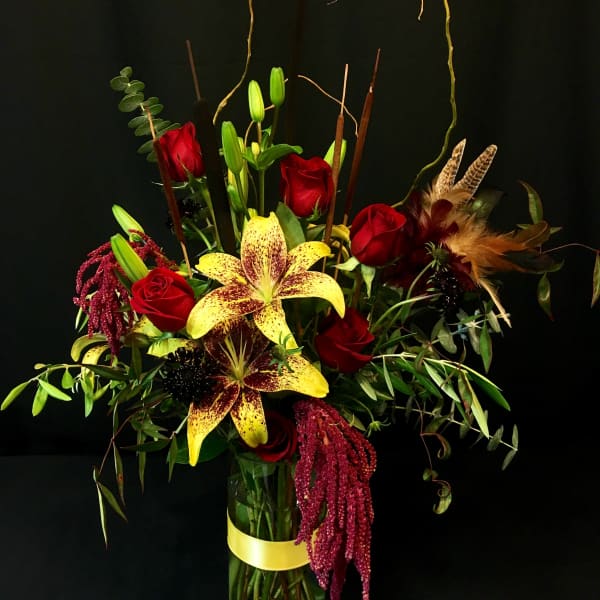Tall bouquet of red roses and yellow lilies in a glass vase