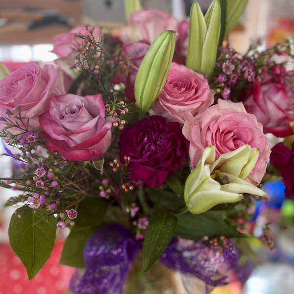 Pink and lavender roses with lilies in a glass vase