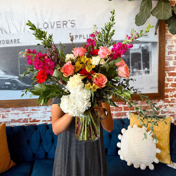 Large mixed bouquet in a glass vase with pink, coral, white, and yellow flowers