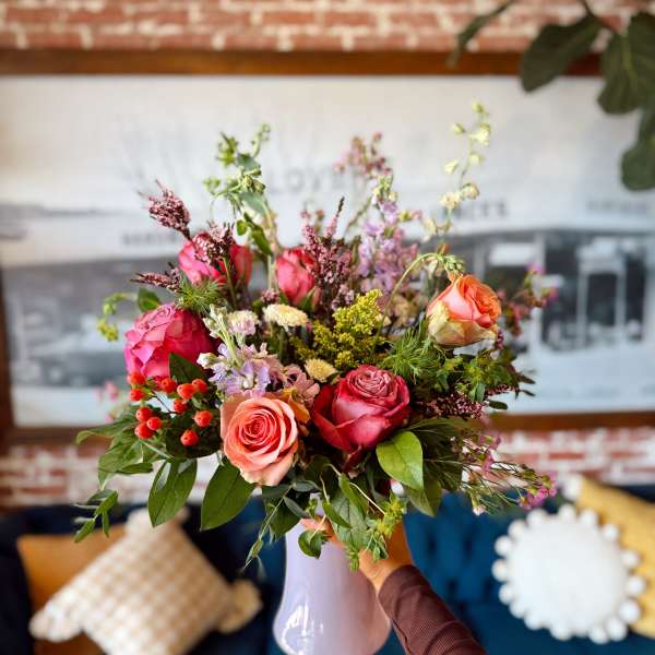 Mixed bouquet of pink and peach roses in a lavender vase