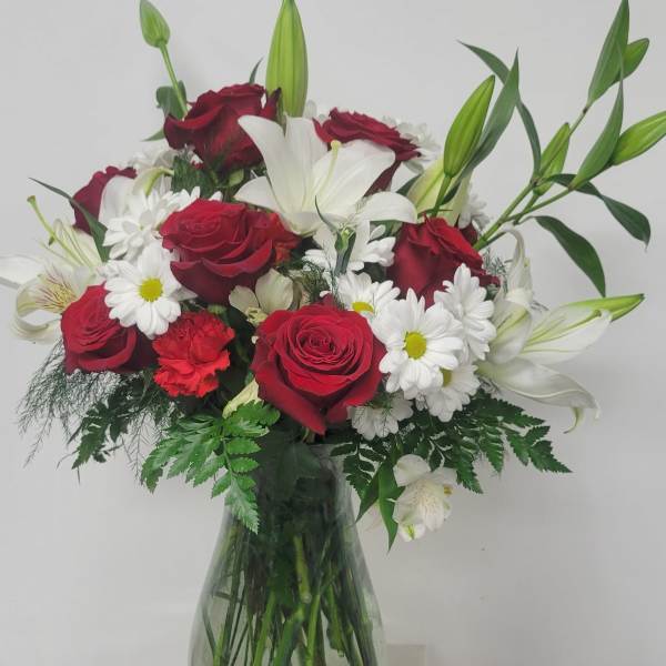 Bouquet of red roses, white lilies, and daisies in a glass vase