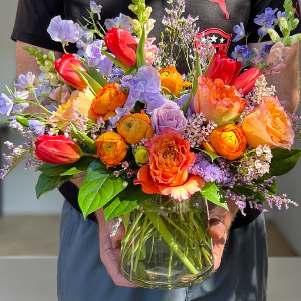 Colorful bouquet of tulips, roses, and ranunculus in a glass vase