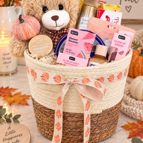 Fall gift basket with a teddy bear, pumpkin decor, and beauty products