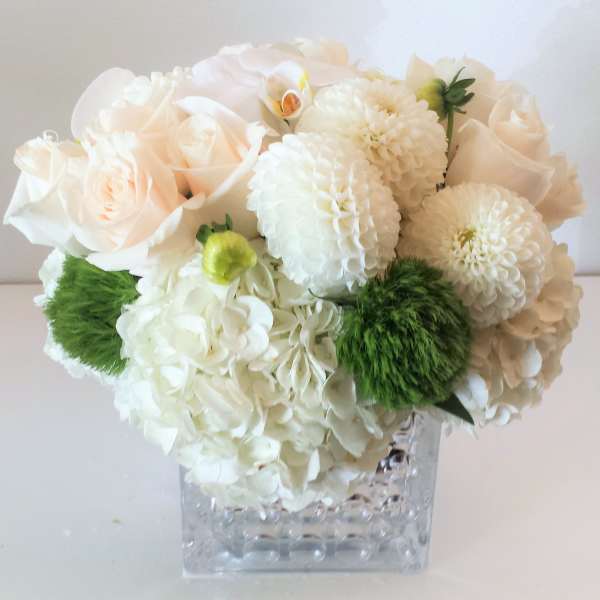 White and blush bouquet in a clear square vase