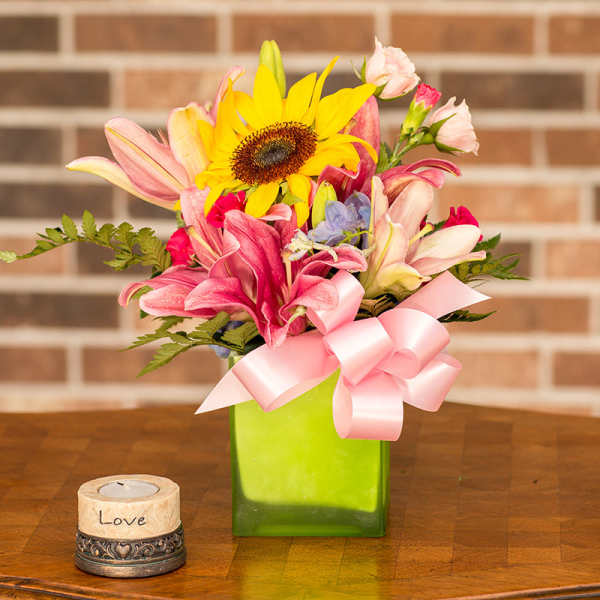 Mixed bouquet with a sunflower and pink lilies in a green vase