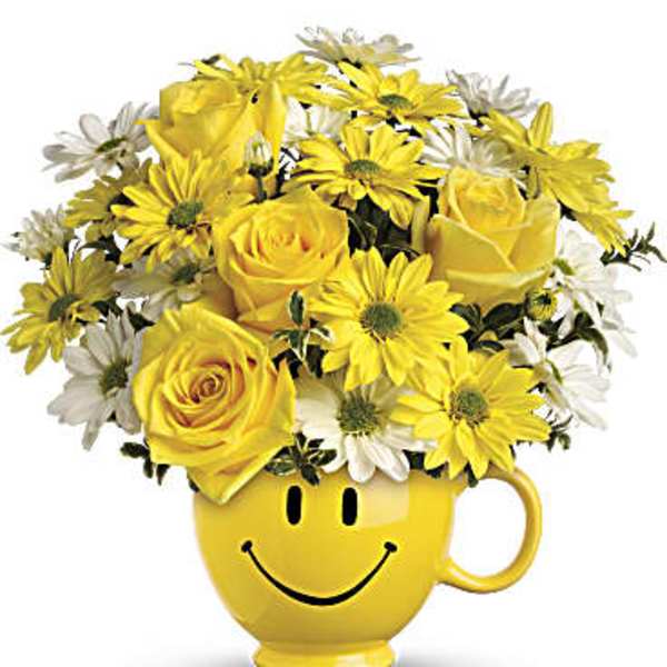 Yellow roses and daisies in a smiley-face mug