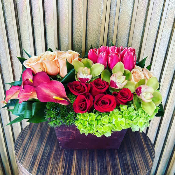 Mixed bouquet with roses, tulips, orchids, and calla lilies in a rectangular vase