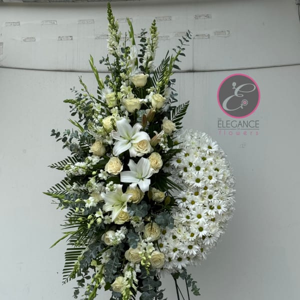 Tall white floral standing spray with lilies, roses, and daisies