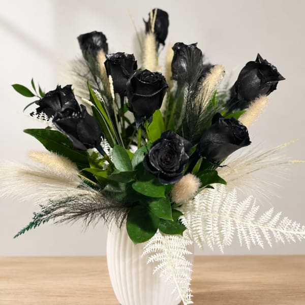 Black roses in a white vase with white feathery accents