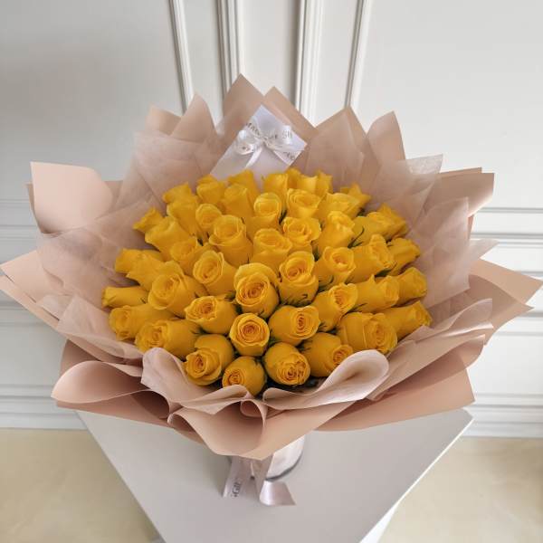 Bouquet of yellow roses wrapped in pale pink paper