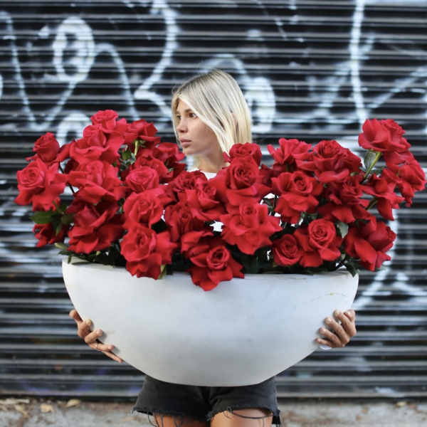 Woman holding a large white bowl filled with red roses