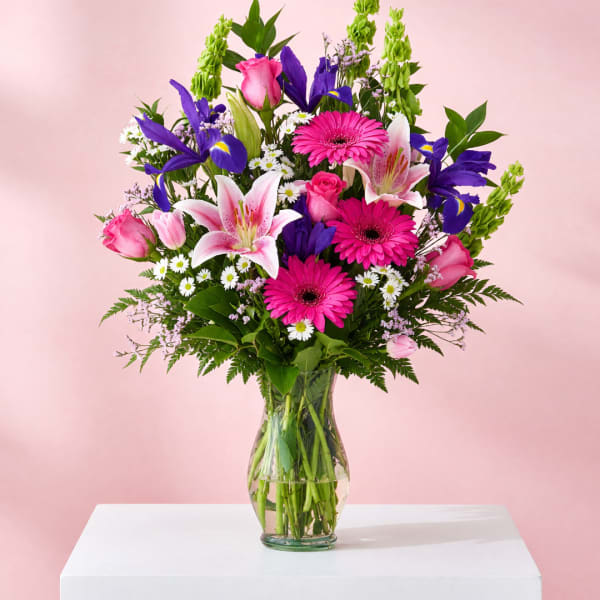 Mixed bouquet of pink, purple, and white flowers in a clear glass vase