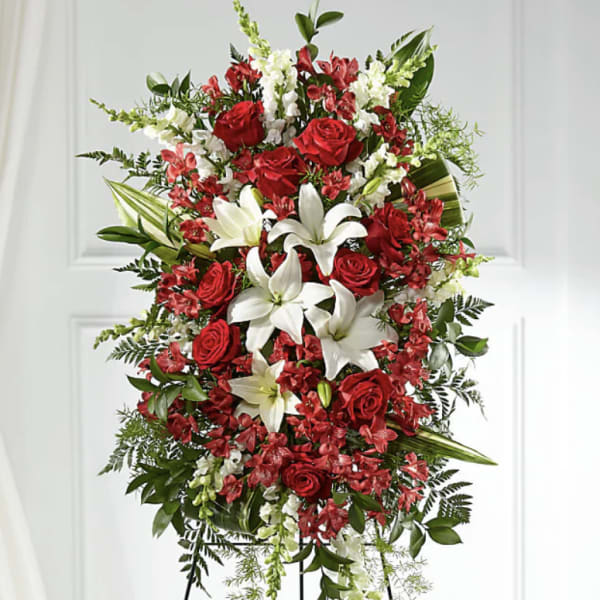 Standing floral spray with red roses and white lilies on a black easel