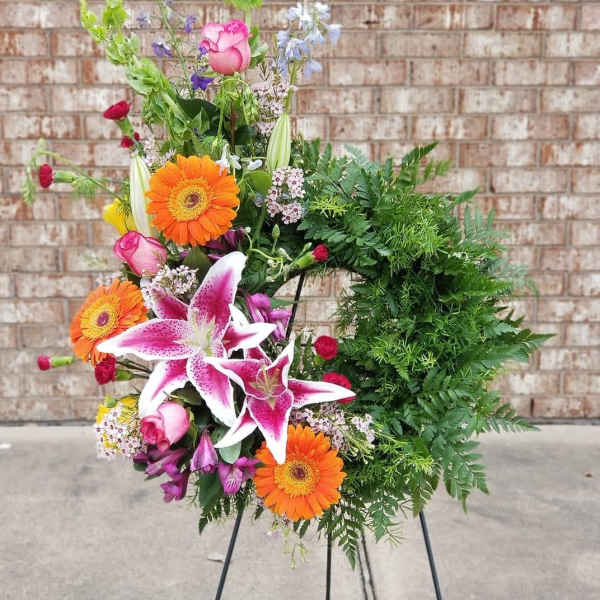 Colorful floral wreath with lilies, gerberas, and roses on a stand