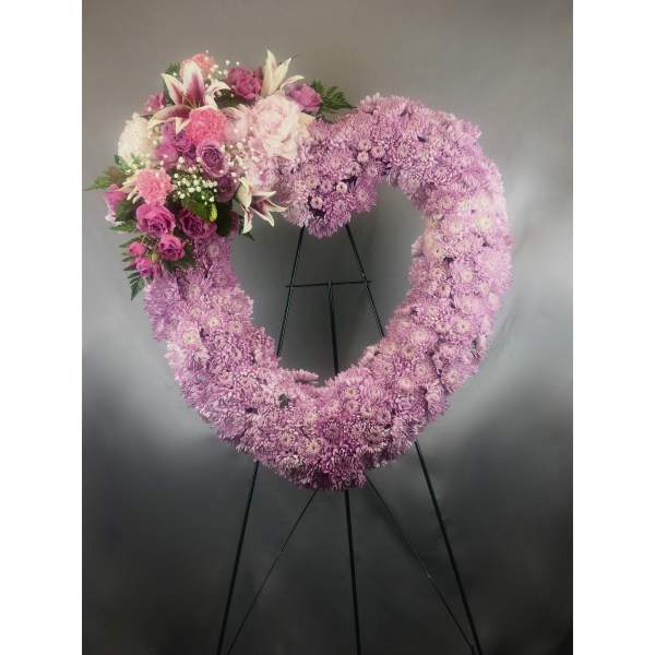 Heart-shaped pink floral wreath on a black stand