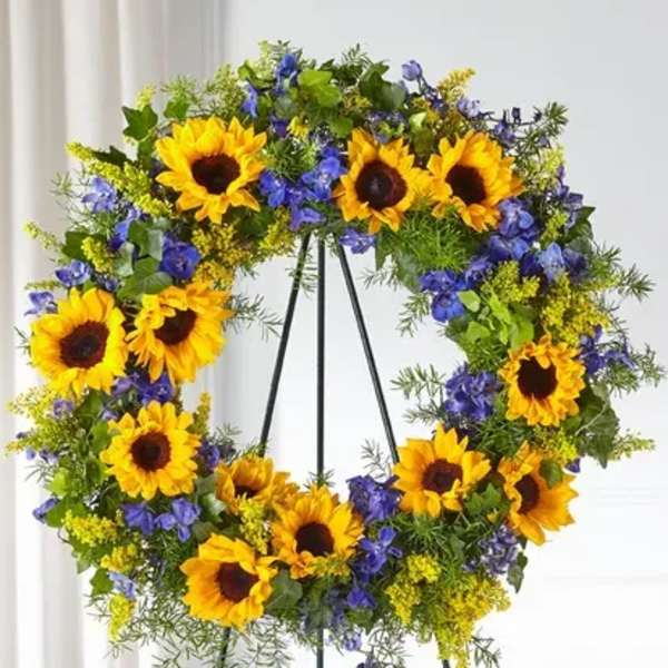 Sunflower wreath with blue flowers on a black stand