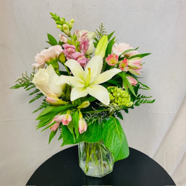 Bouquet of white lilies and pink flowers in a clear glass vase