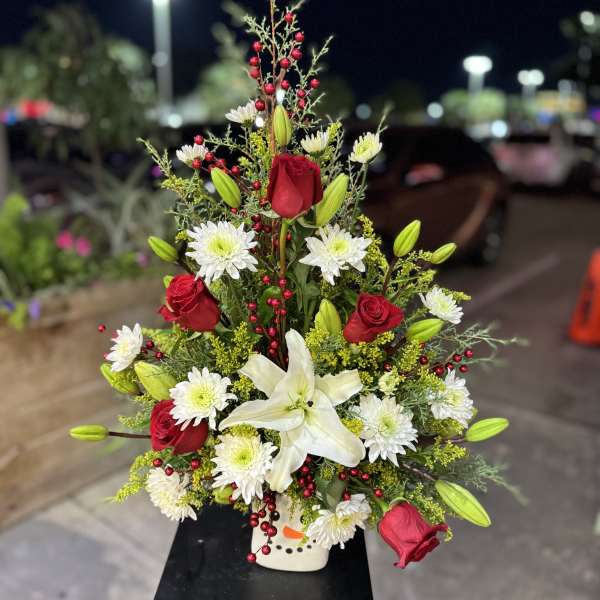 Tall floral arrangement with red roses, white lilies, and white daisies in a vase