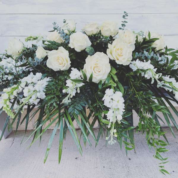 White rose and white floral arrangement with cascading greenery