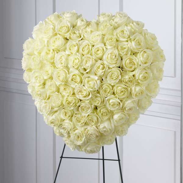 Heart-shaped arrangement of ivory roses on a black metal easel stand