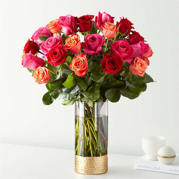 Bouquet of pink, red, and peach roses in a clear glass vase