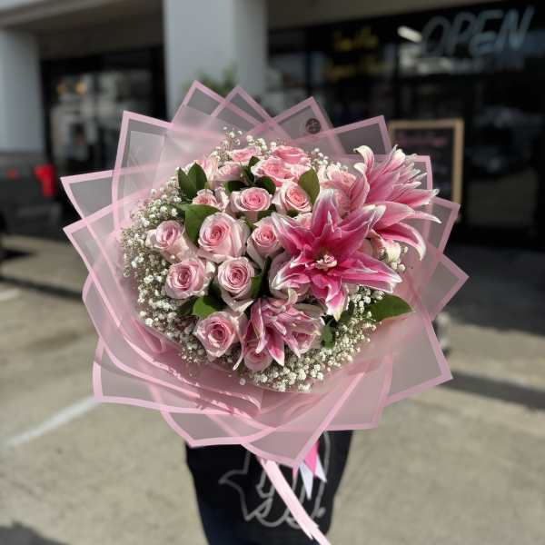 Pink rose bouquet with large pink lilies wrapped in translucent pink paper