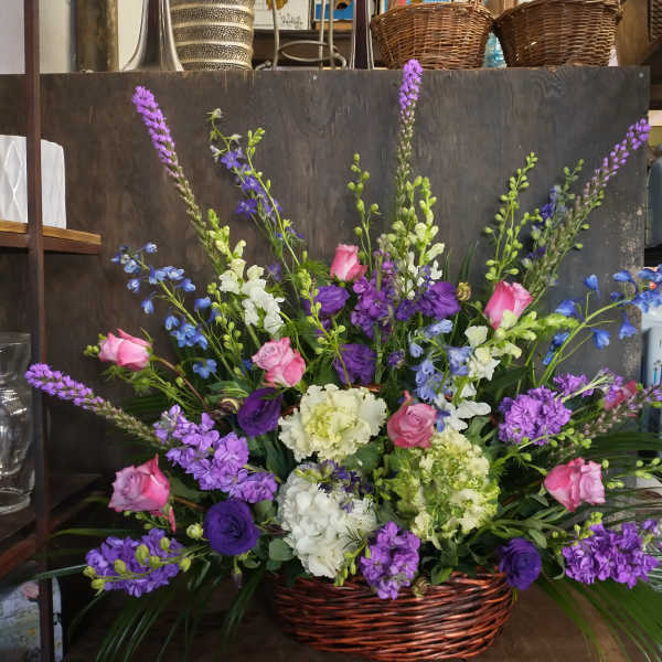 Basket arrangement of pink and purple flowers with white blooms