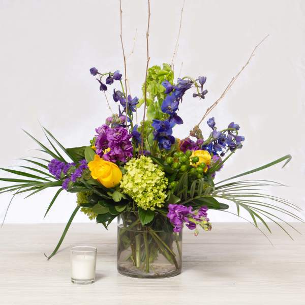 Mixed bouquet in a glass vase with purple, yellow, and green flowers