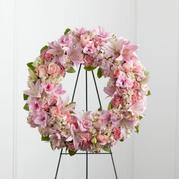 Pink floral wreath on a black stand