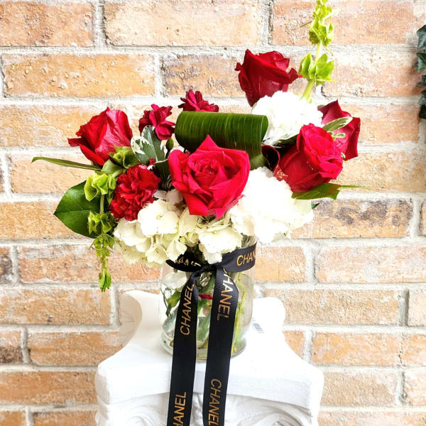 Red roses and white carnations in a glass vase with a black ribbon