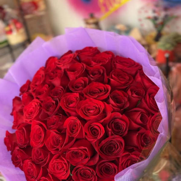 Large bouquet of red roses wrapped in lavender paper
