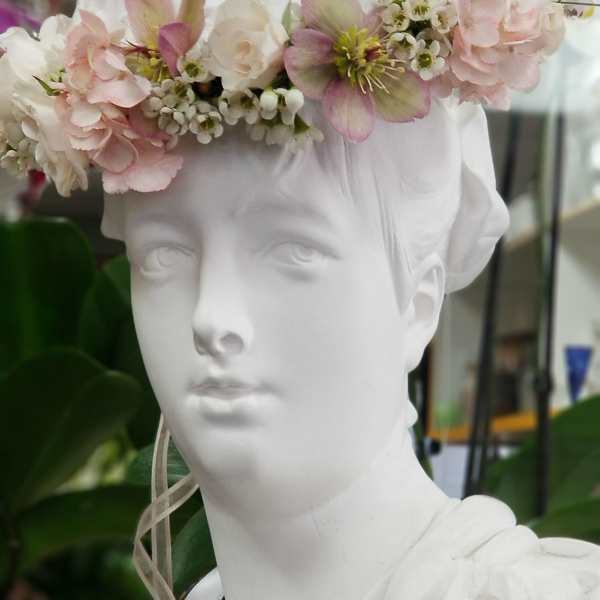White bust wearing a pastel flower crown with pink and white blooms