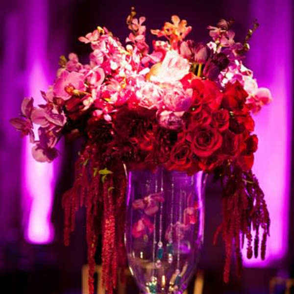 Tall floral centerpiece in a glass vase with red and pink blooms