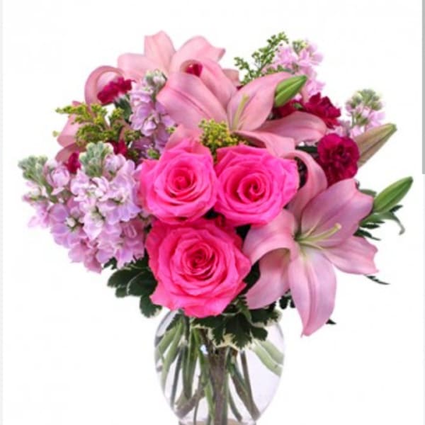 Pink roses and lilies arranged in a clear glass vase