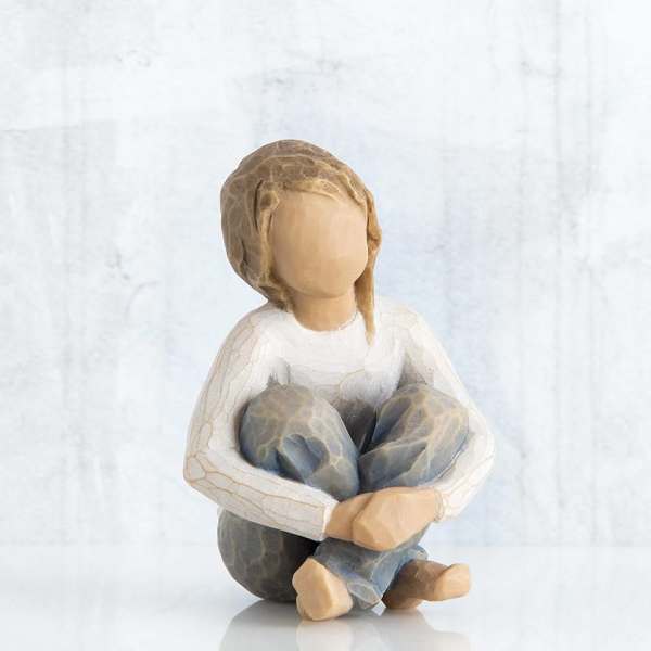 Wooden figurine of a seated child with knees hugged to chest