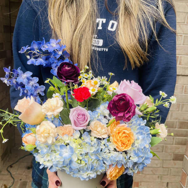 Mixed bouquet in a white vase with blue hydrangeas and roses
