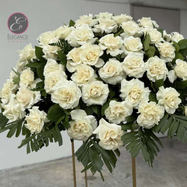 Large dome arrangement of cream roses with palm fronds