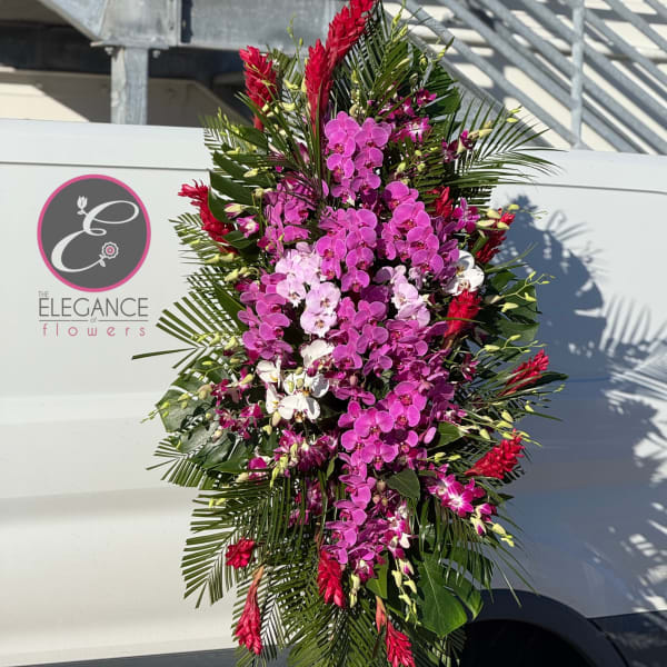 Tall standing floral spray with pink and white orchids and red tropical blooms