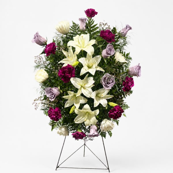 Standing floral spray with white lilies and purple roses on a metal easel