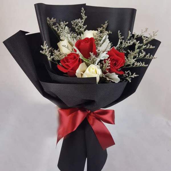 Bouquet of red and white roses wrapped in black paper with a red ribbon
