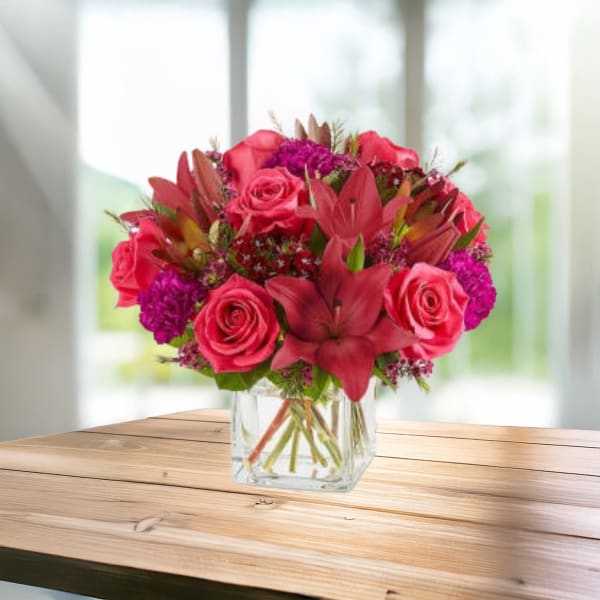 Pink roses and lilies arranged in a clear glass vase