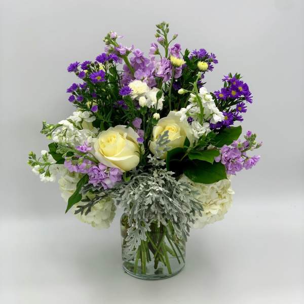 Bouquet of purple and white flowers in a clear glass vase